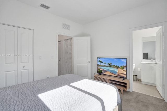 carpeted bedroom with ensuite bathroom and a closet