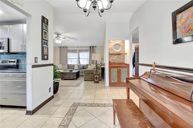 interior space with decorative backsplash, stove, light tile patterned floors, and ceiling fan with notable chandelier