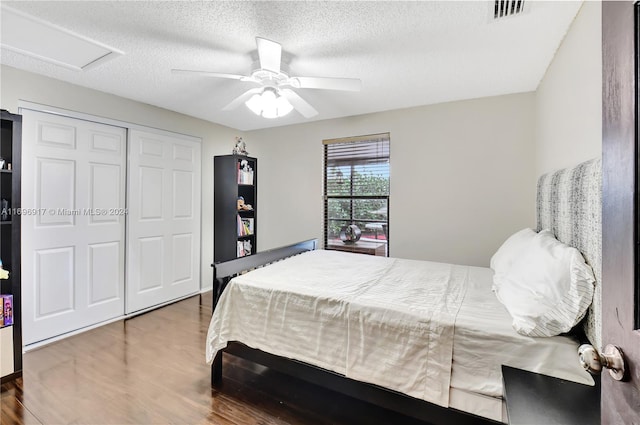 bedroom with a closet, ceiling fan, hardwood / wood-style floors, and a textured ceiling