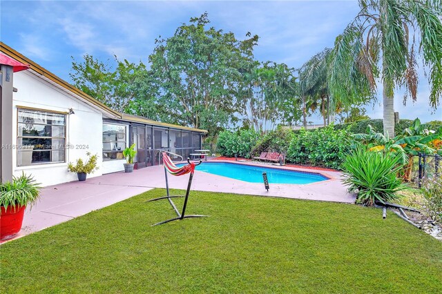 view of swimming pool featuring a patio, a lawn, and a sunroom