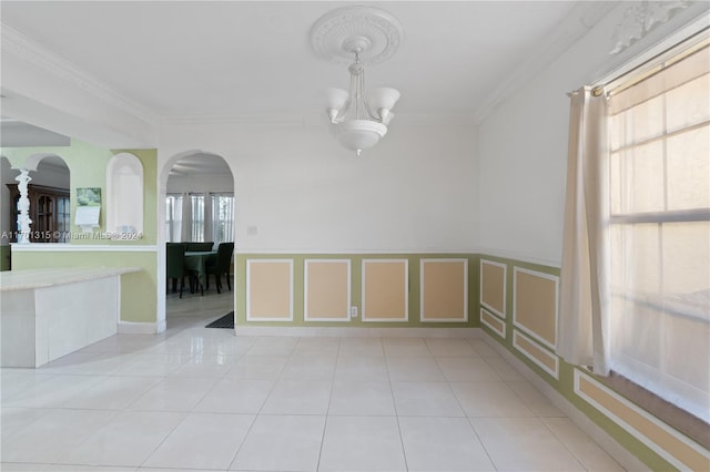 tiled spare room with crown molding and a chandelier