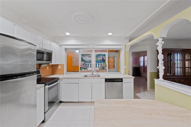 kitchen featuring white cabinets, sink, crown molding, light tile patterned floors, and appliances with stainless steel finishes