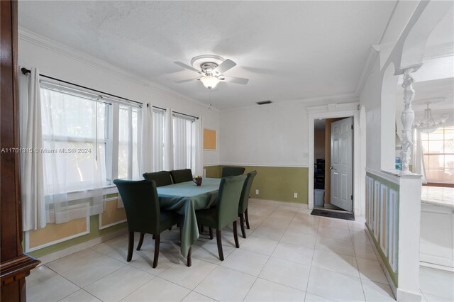 tiled dining space with a textured ceiling, ceiling fan, and ornamental molding