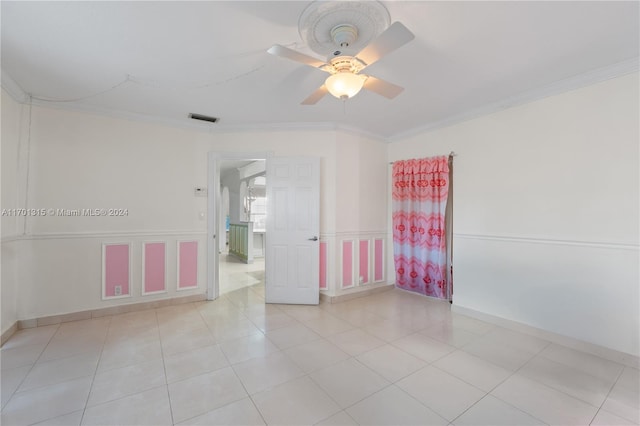 empty room featuring ceiling fan, light tile patterned flooring, and ornamental molding