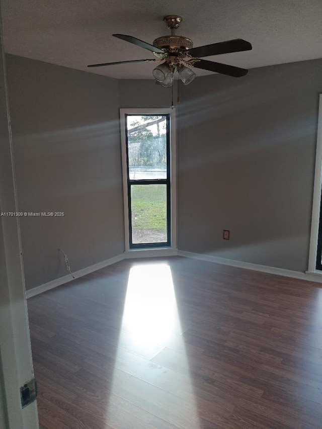 spare room featuring ceiling fan, a healthy amount of sunlight, dark hardwood / wood-style flooring, and a textured ceiling