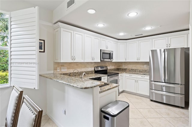 kitchen with a healthy amount of sunlight, light stone counters, backsplash, and appliances with stainless steel finishes