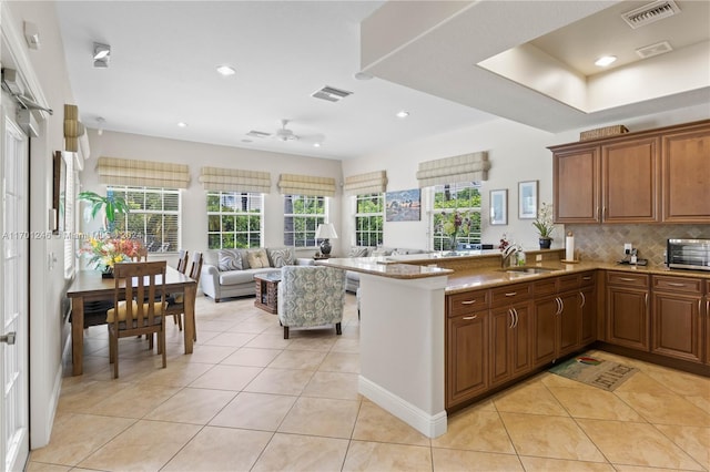 kitchen featuring kitchen peninsula, tasteful backsplash, light tile patterned flooring, and sink