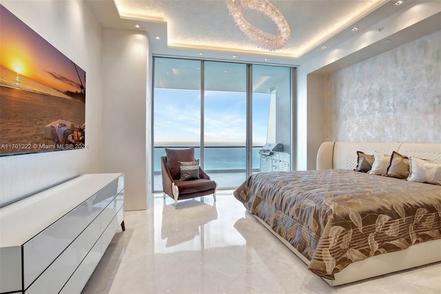 bedroom featuring a tray ceiling, access to exterior, a water view, and a wall of windows