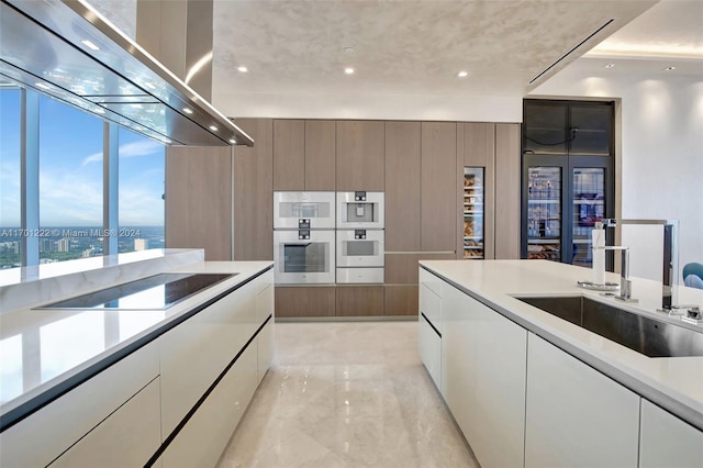 kitchen with sink, double oven, black electric cooktop, white cabinets, and exhaust hood