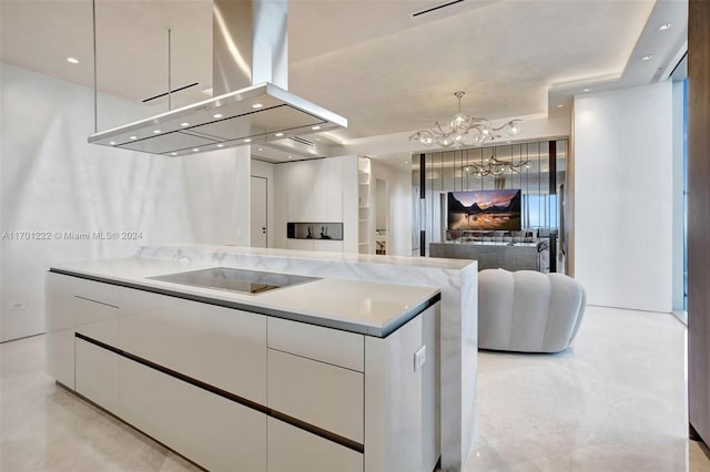 kitchen with island exhaust hood, black electric cooktop, a notable chandelier, white cabinetry, and hanging light fixtures