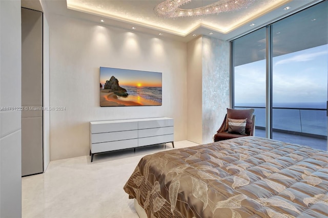 bedroom with a textured ceiling, a tray ceiling, floor to ceiling windows, and a water view