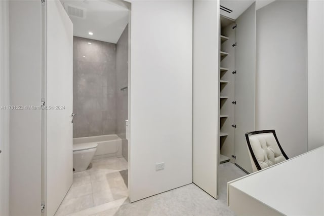 bathroom featuring tile patterned floors, tiled shower / bath combo, and toilet