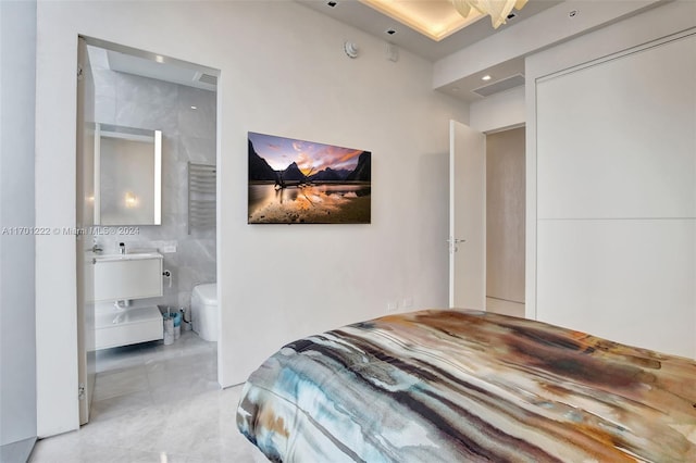 bedroom featuring ensuite bath and tile walls