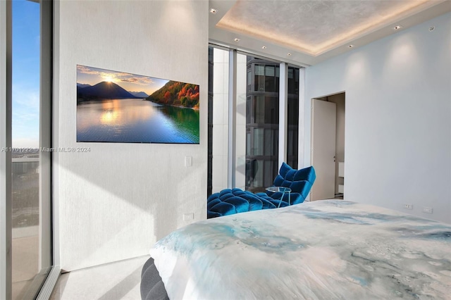 bedroom with a raised ceiling and expansive windows