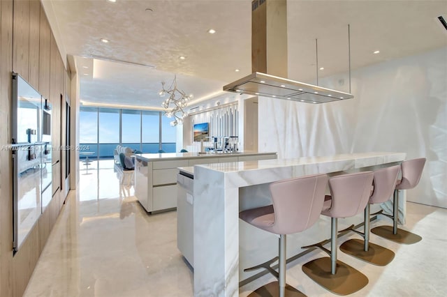 kitchen featuring a center island, island exhaust hood, oven, pendant lighting, and white cabinets