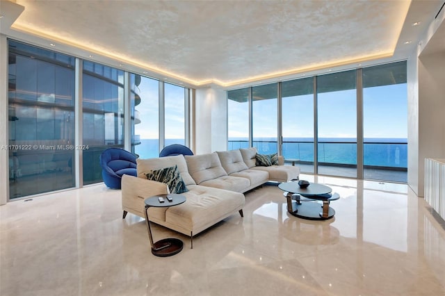 living room featuring a water view, a raised ceiling, and expansive windows