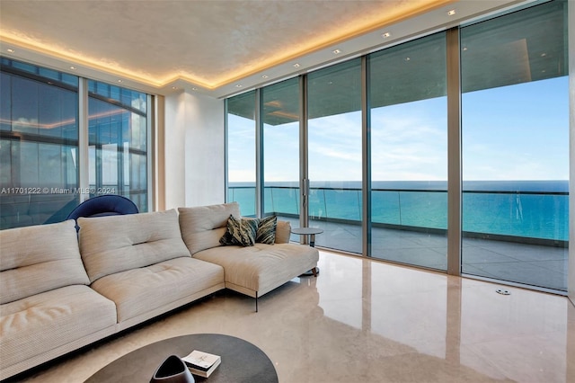 living room with a water view, expansive windows, and a tray ceiling