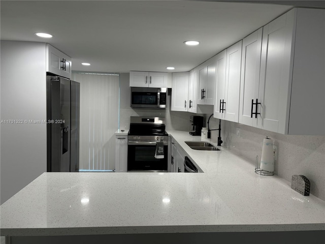 kitchen featuring kitchen peninsula, appliances with stainless steel finishes, white cabinetry, and sink