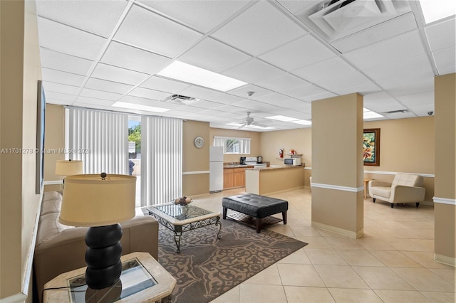 living room with a paneled ceiling, ceiling fan, and light tile patterned floors