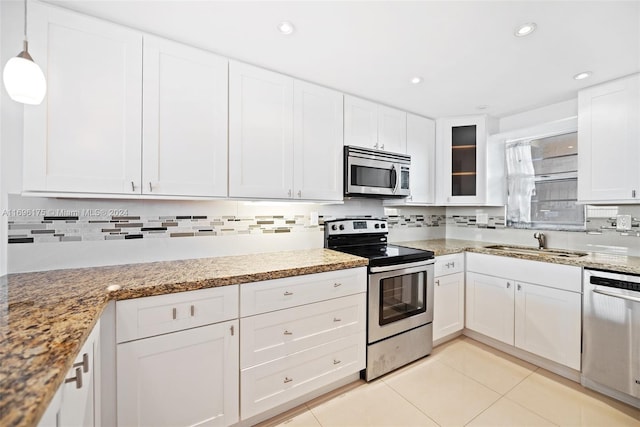 kitchen featuring appliances with stainless steel finishes, sink, light tile patterned floors, white cabinetry, and hanging light fixtures