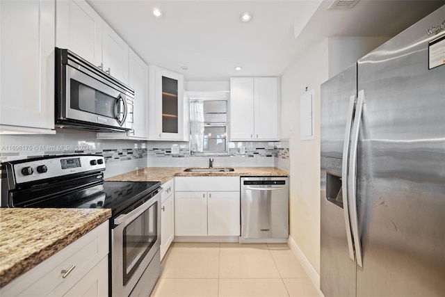 kitchen featuring sink, light tile patterned floors, light stone countertops, appliances with stainless steel finishes, and white cabinetry