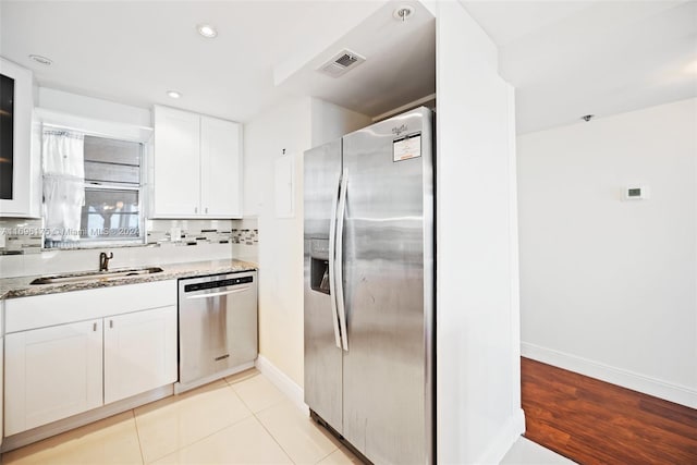 kitchen with decorative backsplash, light stone counters, stainless steel appliances, sink, and white cabinetry