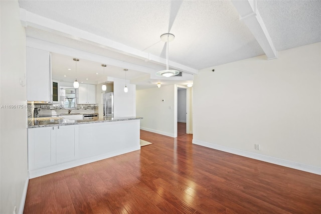 kitchen featuring white cabinetry, stainless steel fridge, hardwood / wood-style floors, pendant lighting, and a textured ceiling