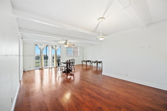 unfurnished dining area with beamed ceiling, ceiling fan, wood-type flooring, and a textured ceiling