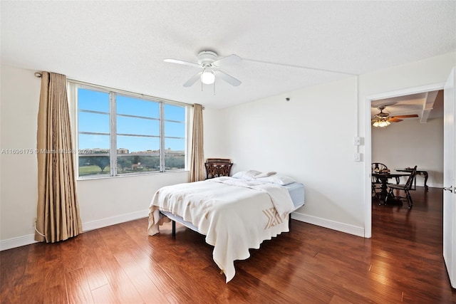 bedroom featuring ceiling fan, dark wood-type flooring, and a textured ceiling