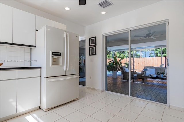 kitchen featuring ceiling fan, white cabinets, white refrigerator with ice dispenser, decorative backsplash, and light tile patterned floors