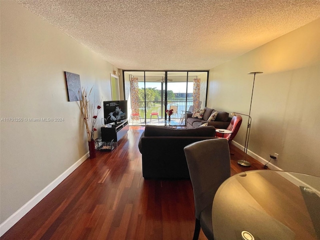 living room featuring dark hardwood / wood-style flooring, a textured ceiling, and a wall of windows