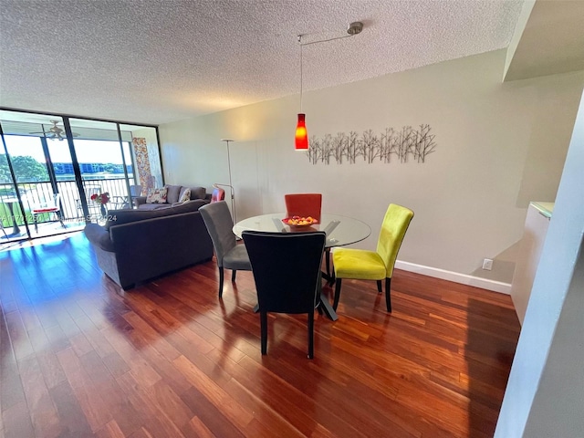 dining area with dark hardwood / wood-style floors, expansive windows, and a textured ceiling