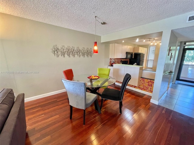 dining room with a textured ceiling and dark hardwood / wood-style floors