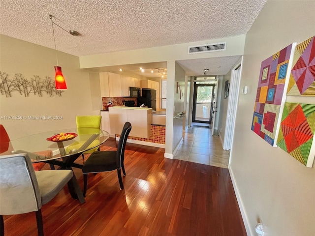 dining area with hardwood / wood-style floors and a textured ceiling