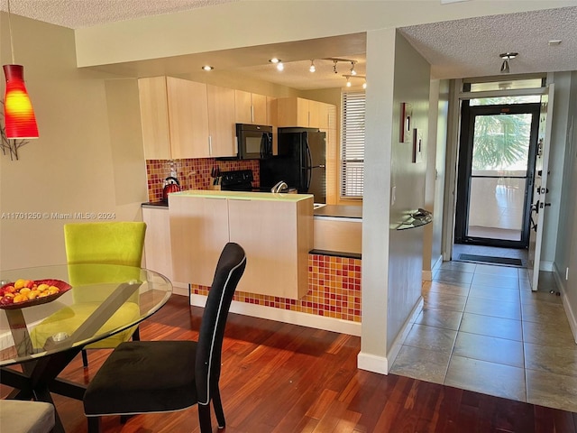 kitchen featuring tasteful backsplash, kitchen peninsula, a textured ceiling, black appliances, and hardwood / wood-style flooring