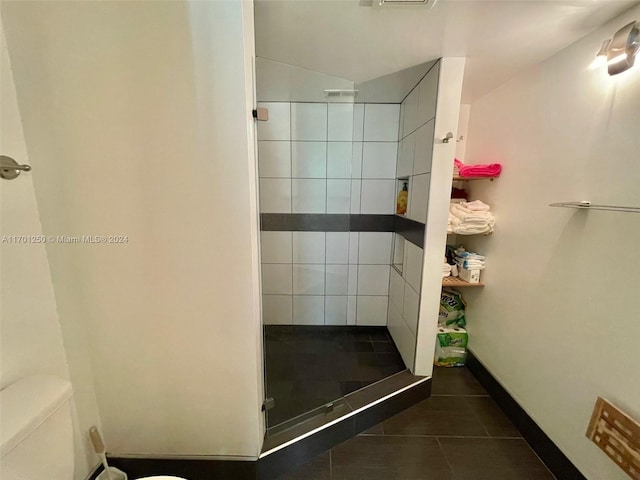 bathroom featuring a tile shower, tile patterned flooring, and toilet