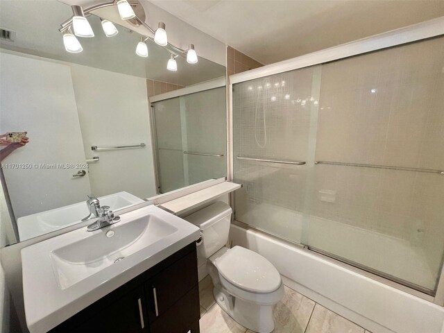 full bathroom with tile patterned flooring, vanity, enclosed tub / shower combo, and toilet