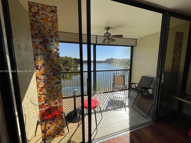 balcony with ceiling fan and a water view