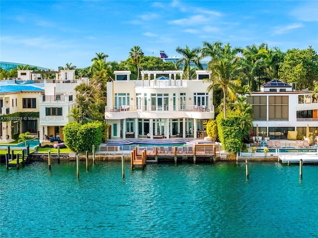 back of property with a water view and a balcony