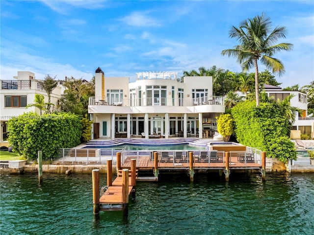 rear view of property with a patio, a water view, a balcony, and a swimming pool