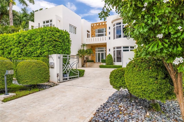 271 N Hibiscus Dr, Miami Beach, FL 33139 - art deco inspired home with stucco siding, a balcony, stone siding, a gate, and a fenced front yard