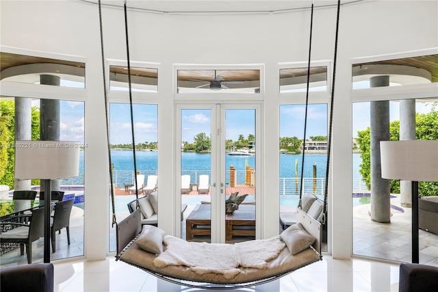 entryway with ceiling fan, a water view, and light tile patterned floors