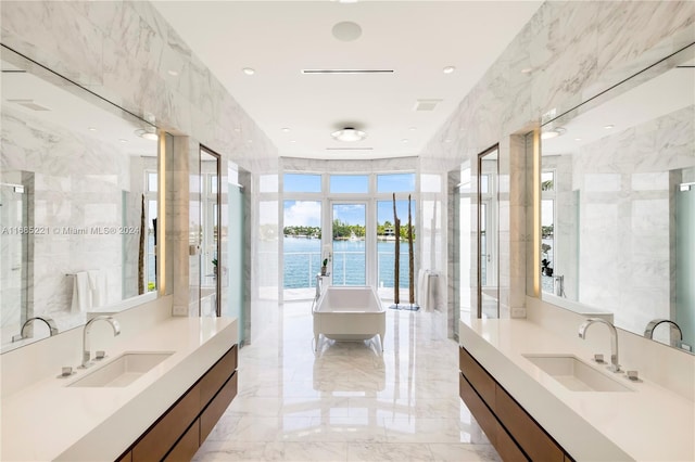 bathroom with vanity, shower with separate bathtub, a water view, and tile walls