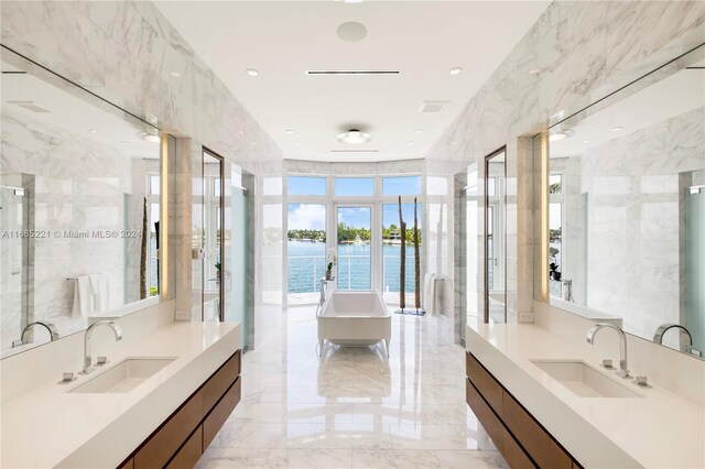 271 N Hibiscus Dr, Miami Beach, FL 33139 - bathroom featuring a water view, a freestanding bath, two vanities, and marble tiled floors