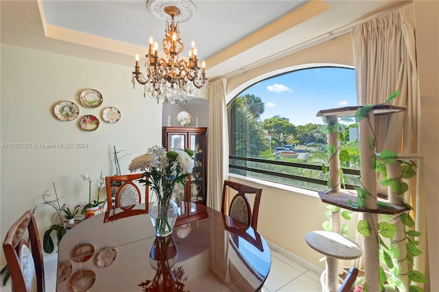 dining space with light tile patterned floors, a tray ceiling, and an inviting chandelier