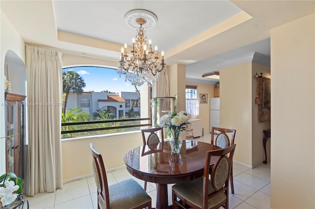 tiled dining space featuring a raised ceiling, a wealth of natural light, and a chandelier