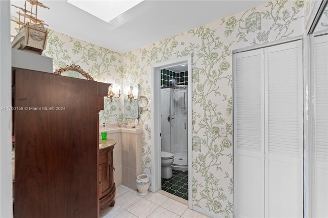 bathroom with a skylight, tile patterned floors, an enclosed shower, toilet, and vanity