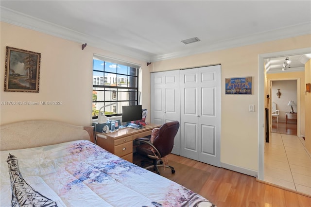 bedroom featuring light wood-type flooring, a closet, and crown molding