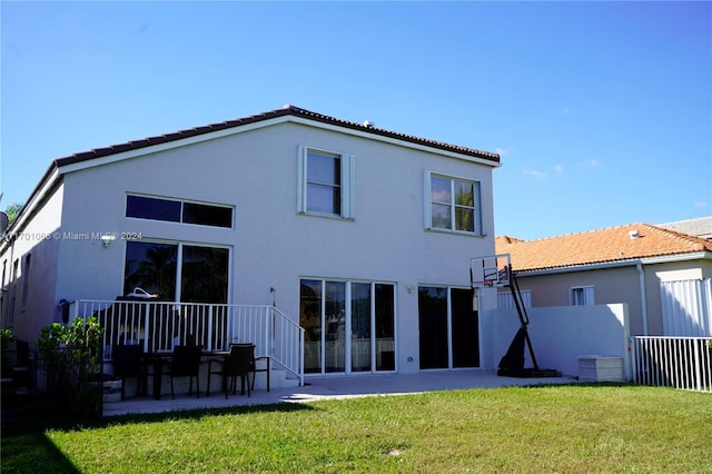 rear view of property featuring a lawn, basketball court, and a patio