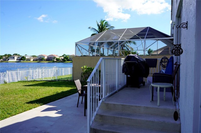 view of patio with glass enclosure and a water view